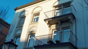 A multi-story building with a classic architectural style, featuring arched windows and a balcony with metal railings. - KÖNIGSschlaf's large vacation apartment for up to 3-5 people with sunny balcony (Konstanz)