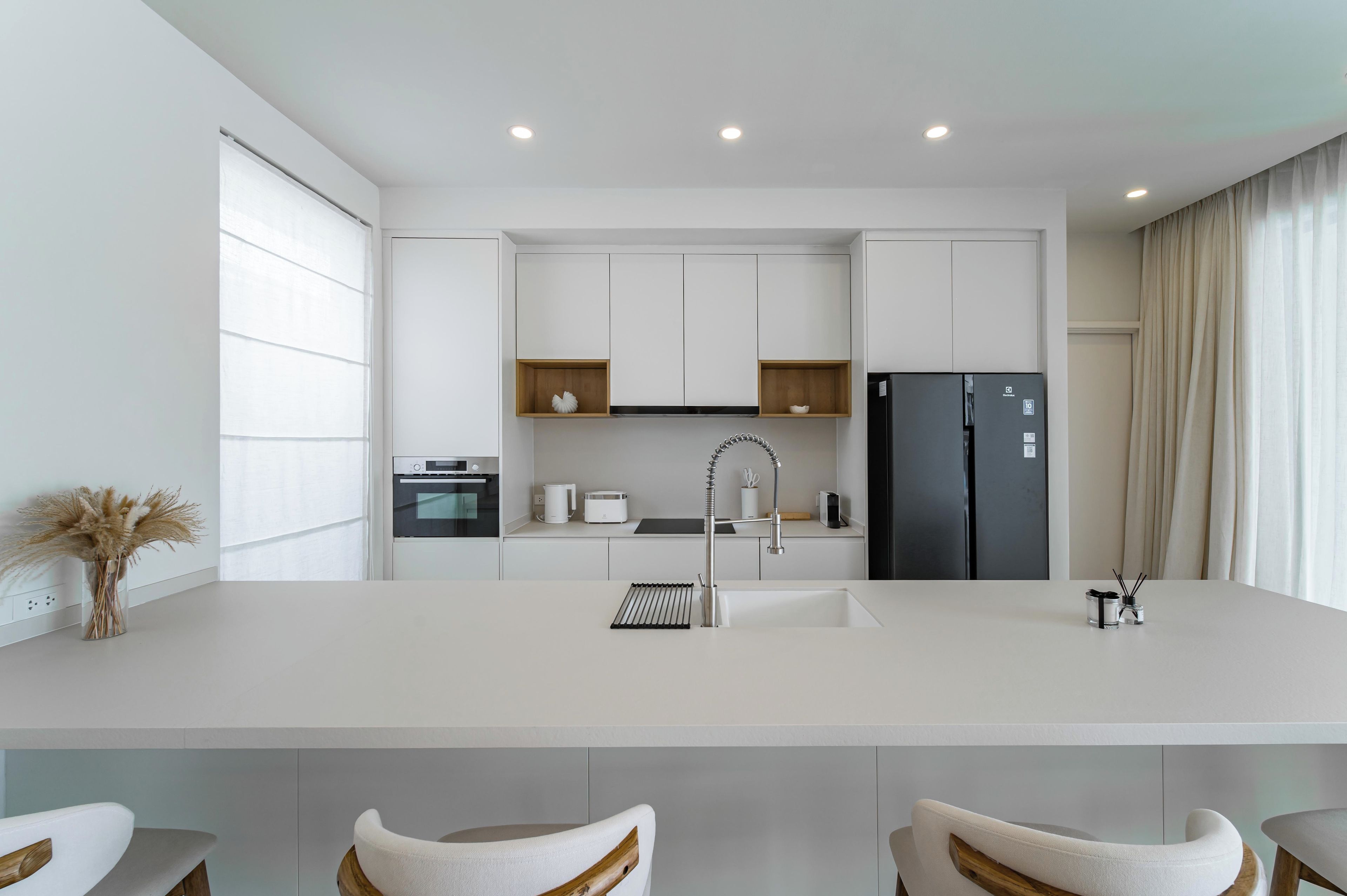 Een moderne keuken met witte kasten, een centraal eiland en een ingebouwde oven.
