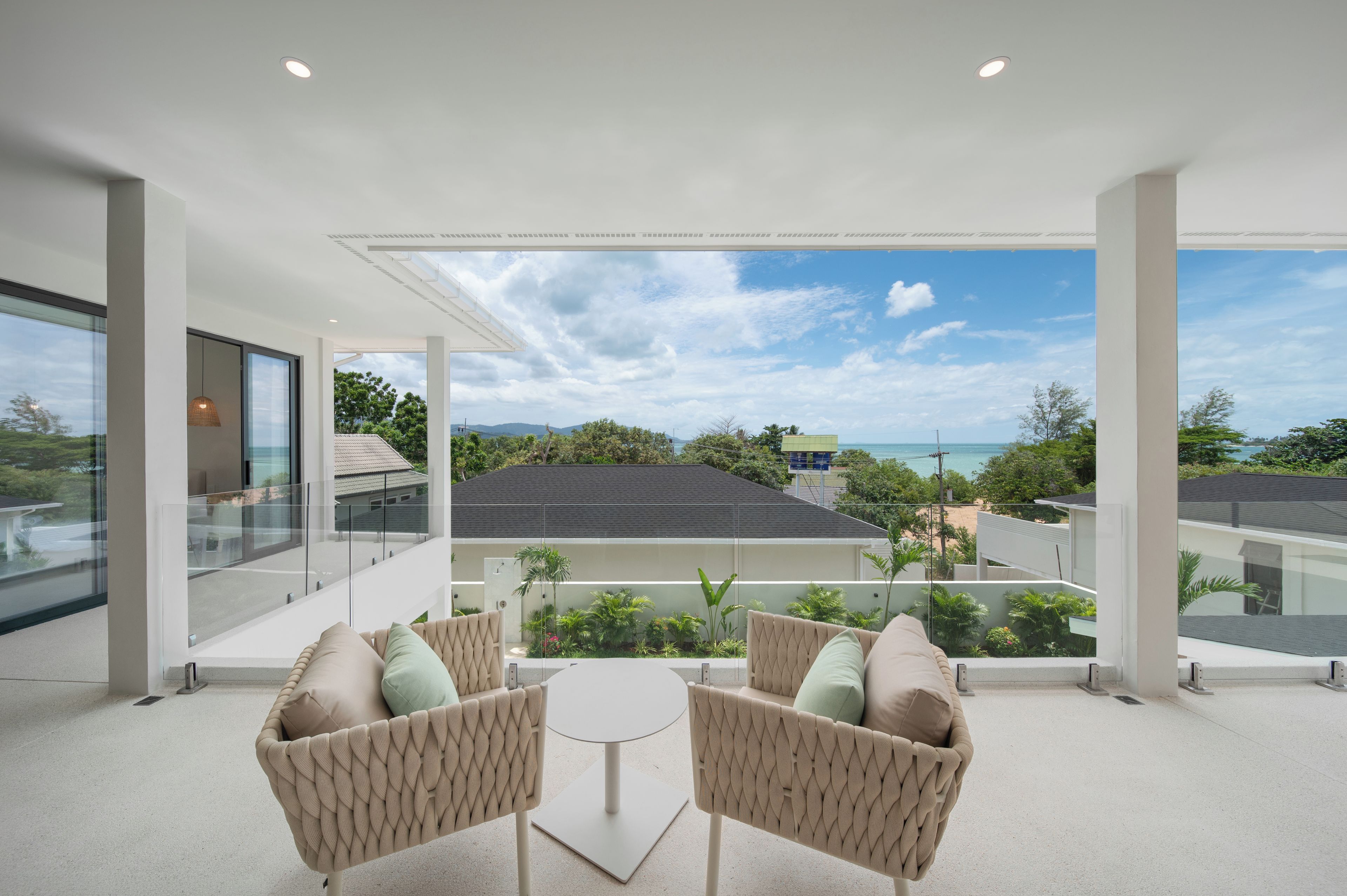A modern outdoor seating area with a view of the ocean and surrounding buildings.