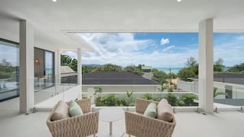 A modern outdoor seating area with a view of the ocean and surrounding buildings.