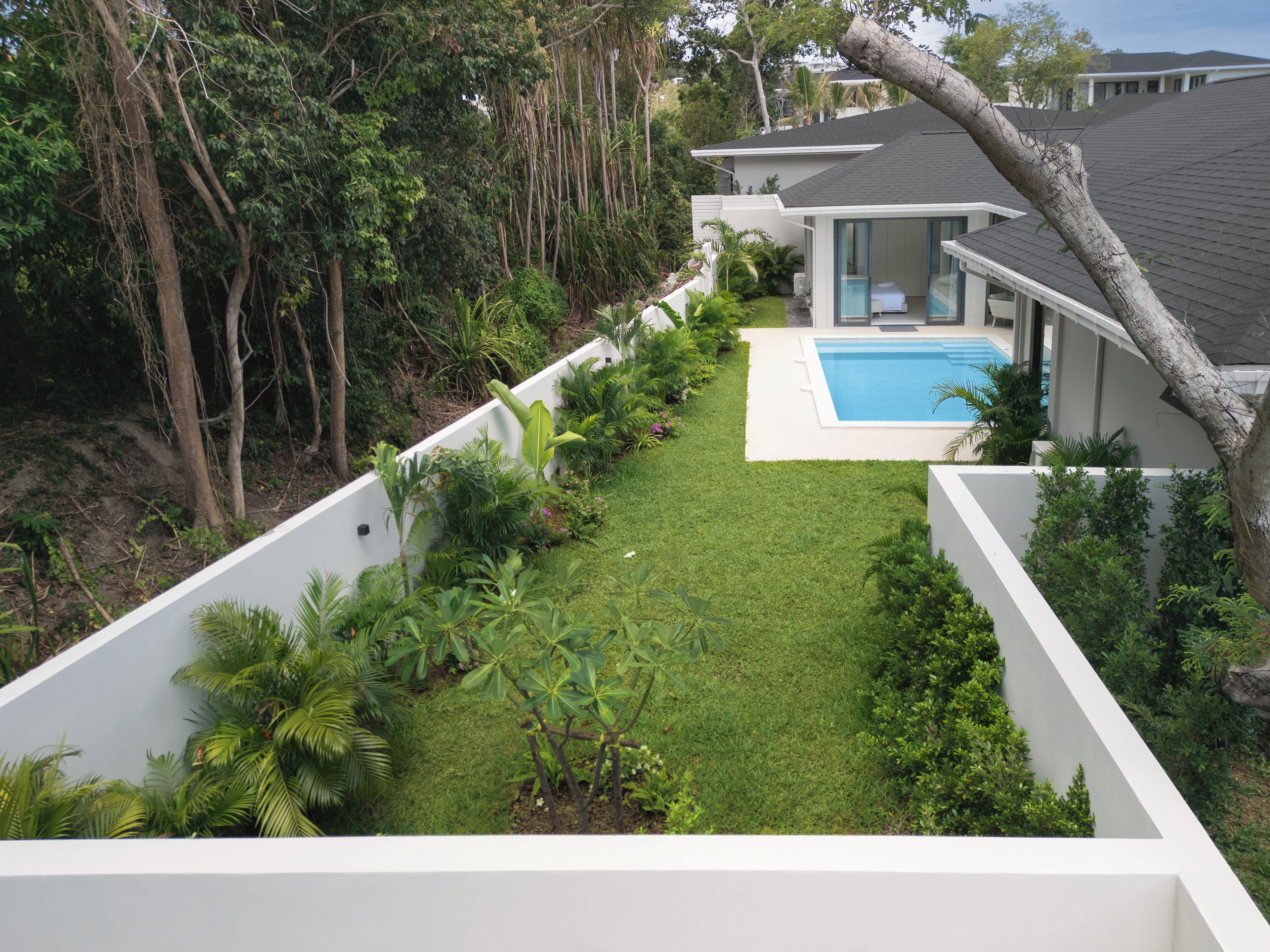 Ein modernes Haus mit Swimmingpool, umgeben von üppiger Vegetation und einem gepflegten Rasen.