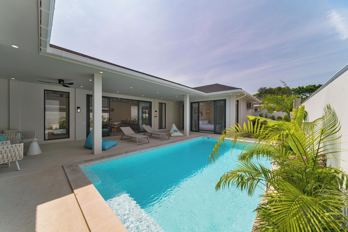 A modern house with a swimming pool, outdoor seating, and a covered patio area.