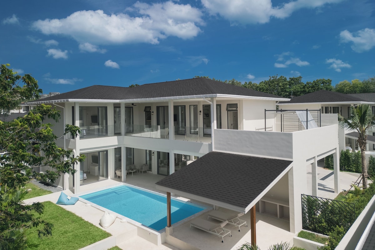 A modern two-story house with a swimming pool, large glass windows, and a flat roof.