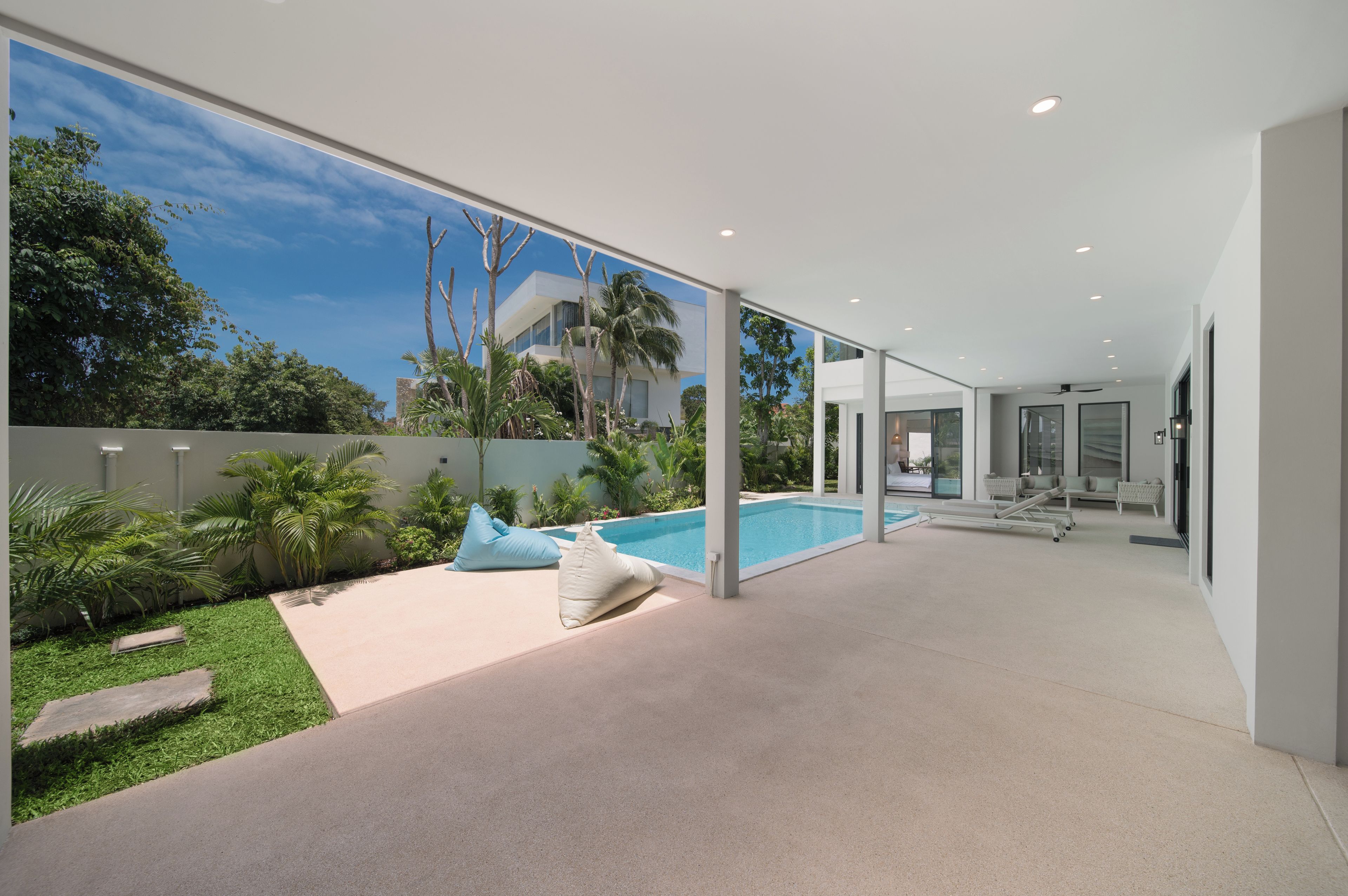 A modern house with a swimming pool, outdoor seating, and a view of the surrounding area.