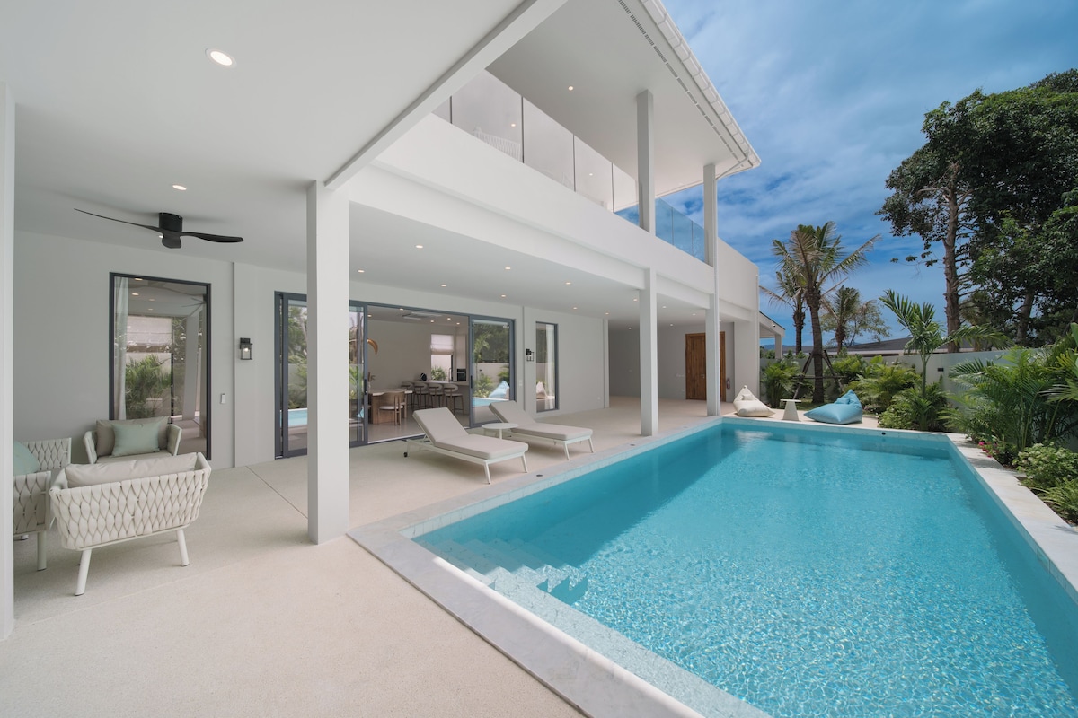 A modern poolside area with lounge chairs and a clear blue pool.