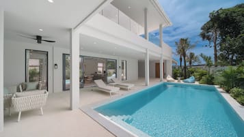 A modern poolside area with lounge chairs and a clear blue pool.