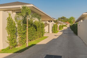 A residential street with houses, a sidewalk, and greenery. - Valentine Village (Koh Samui)