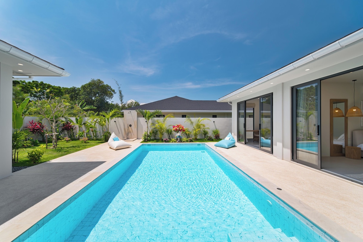 A modern house with a swimming pool, a patio with seating, and a well-maintained garden.