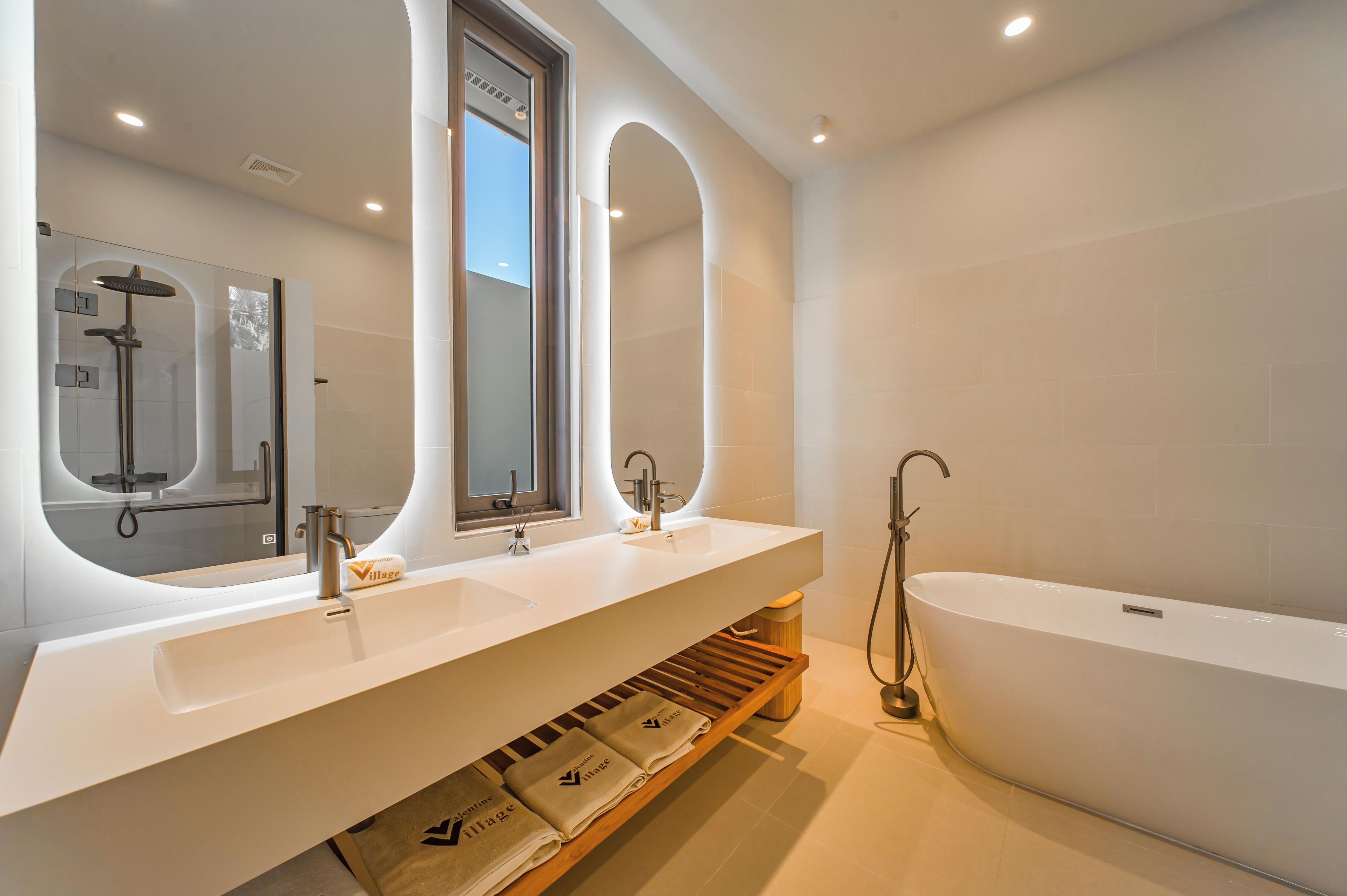 A modern bathroom with a large bathtub, two sinks, and a shower.
