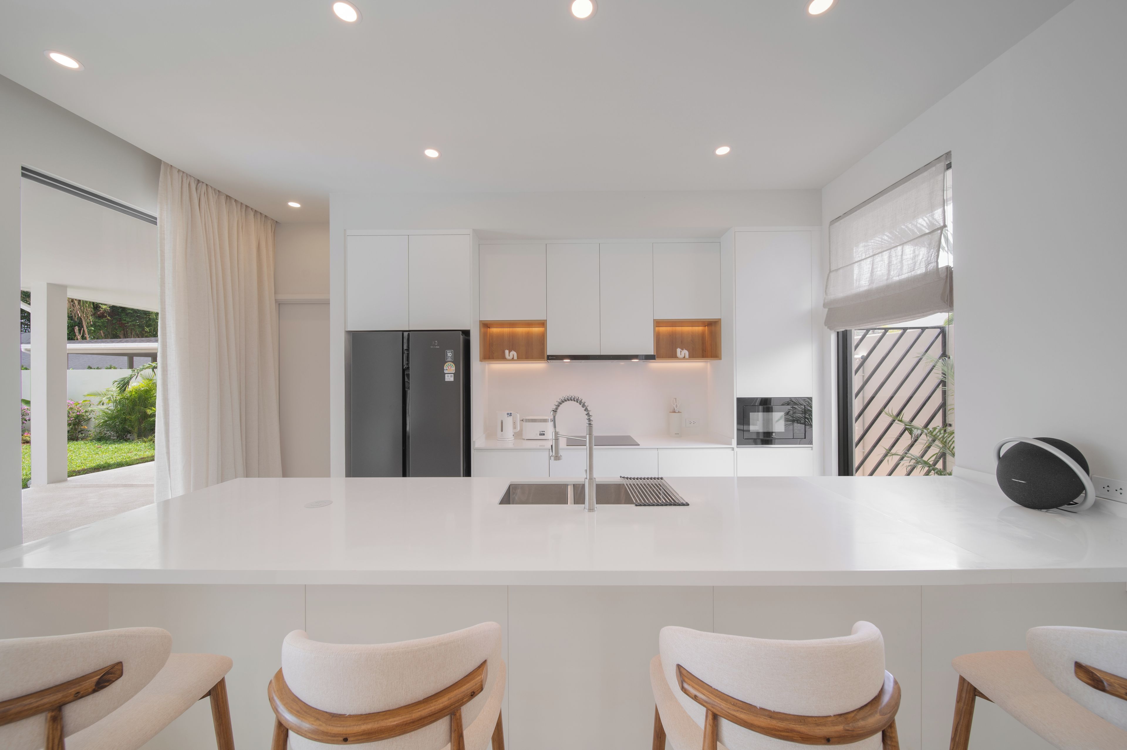 Una cocina moderna con una isla central, electrodomésticos de acero inoxidable y vistas a un jardín.