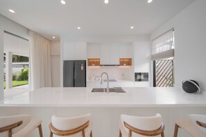 Una cocina moderna con una isla central, electrodomésticos de acero inoxidable y vistas a un jardín.