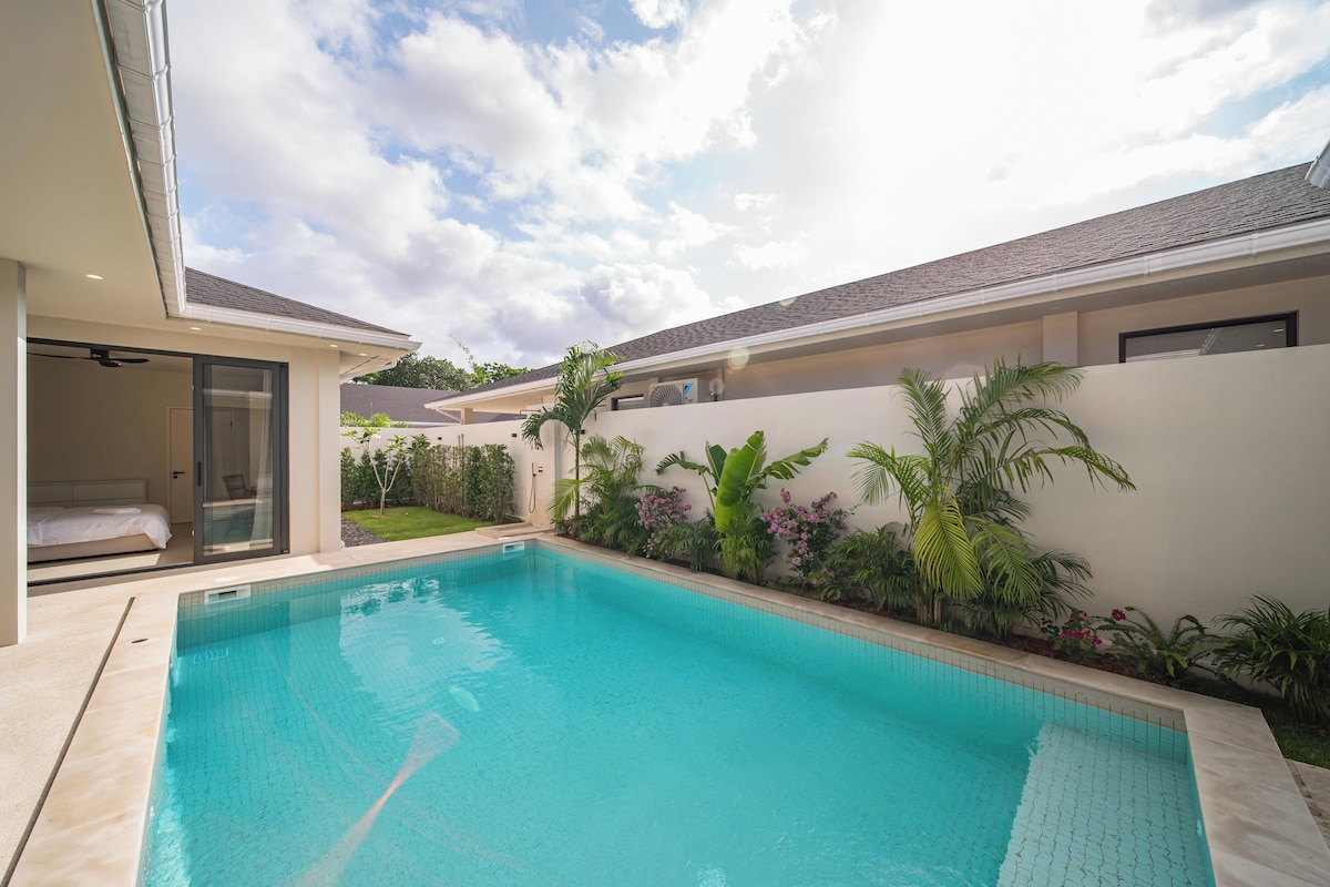 A modern house with a swimming pool, a covered patio, and a view of the sky.