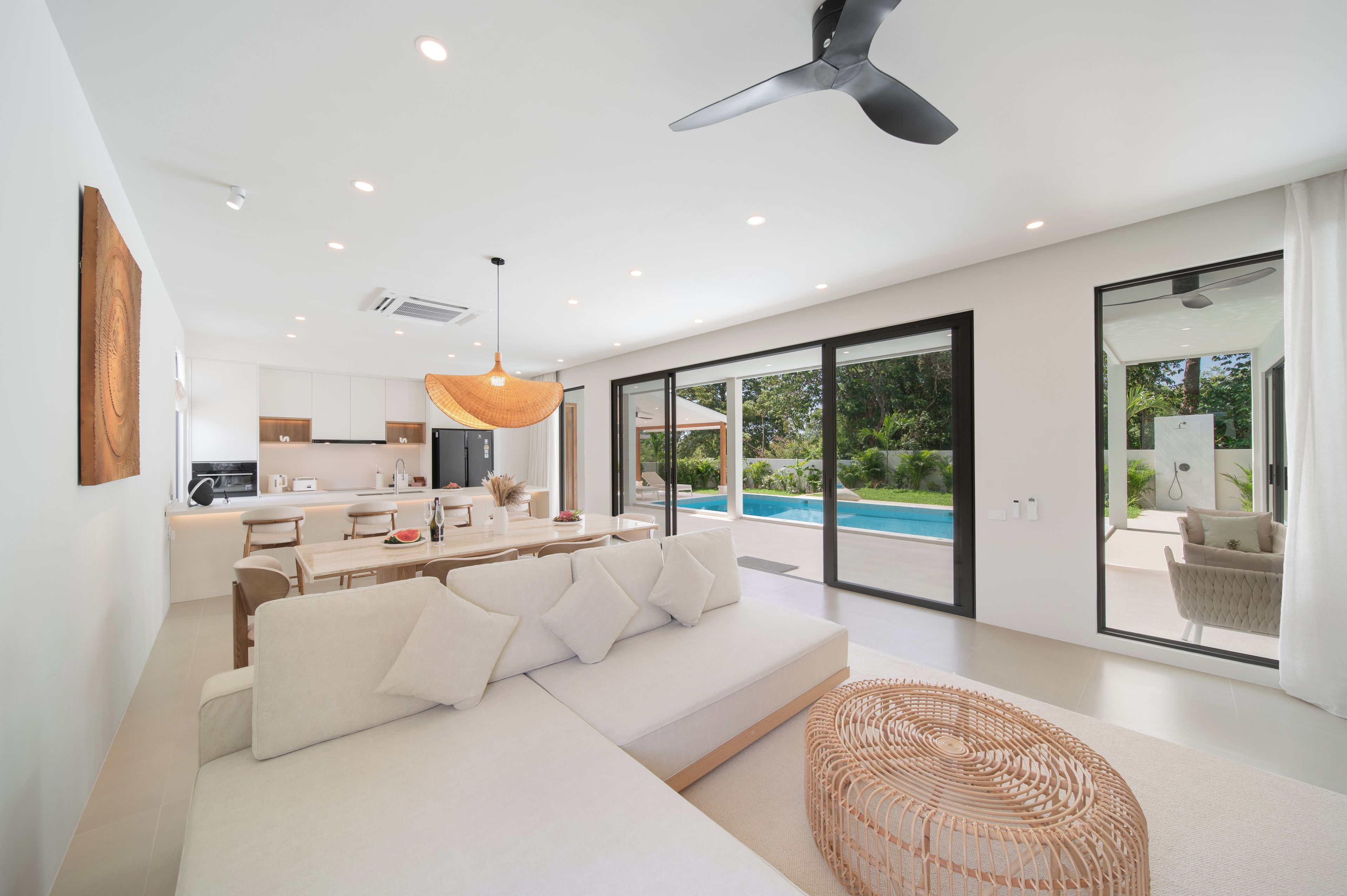 Un soggiorno moderno con un divano bianco, una zona pranzo e vista su una piscina.