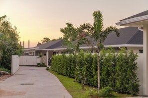 A residential area with modern houses, a paved driveway, and well-maintained greenery. - Valentine Village (Koh Samui)