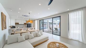 Una sala moderna con un sofá, una mesa de comedor y una cocina al fondo.