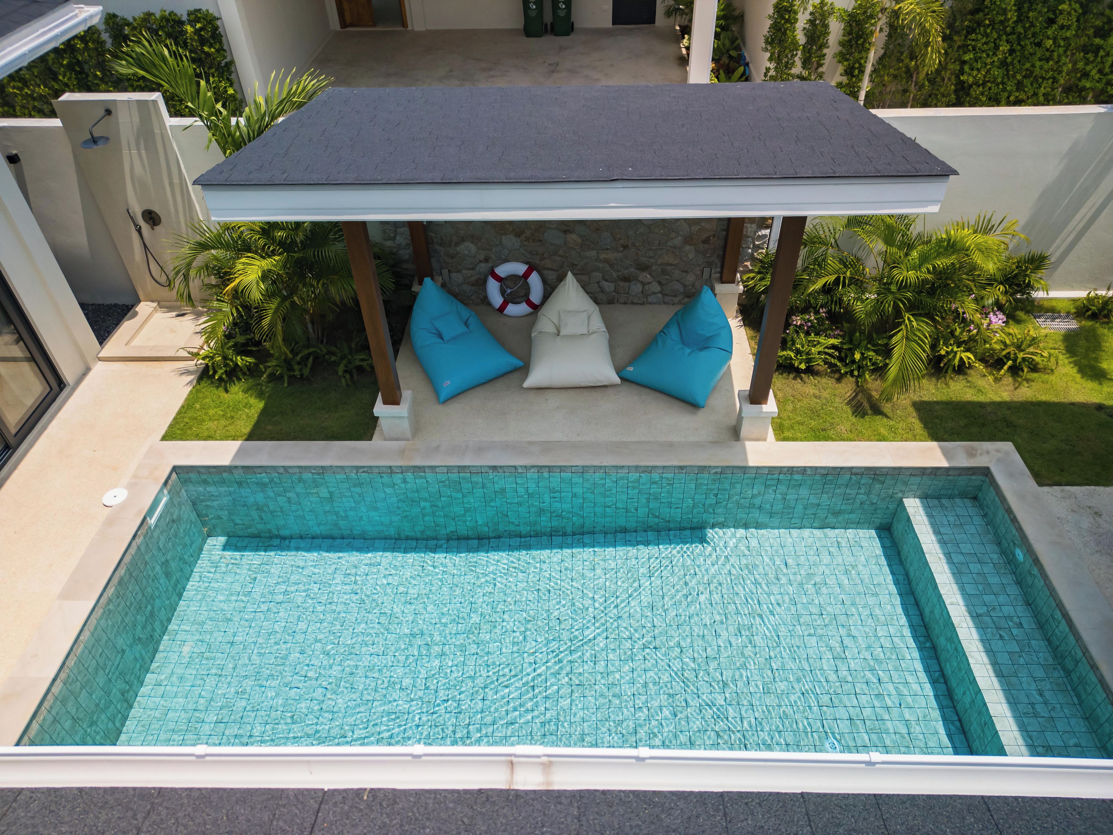 A swimming pool with a covered seating area and a stone wall.
