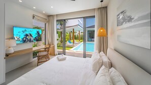 A modern hotel room with a bed, TV, and a view of a swimming pool. - Valentine Village (Koh Samui)