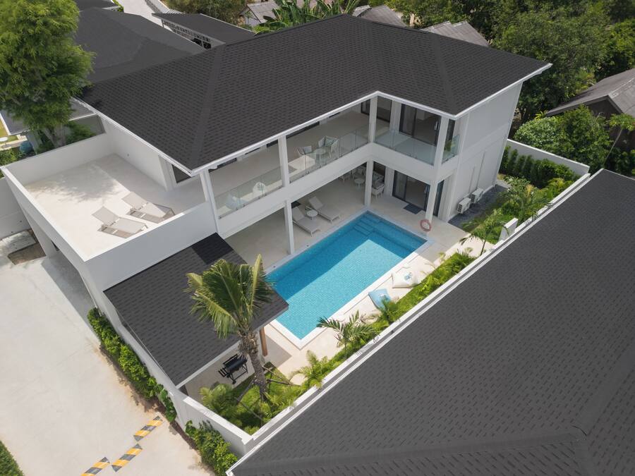 Uma casa de dois andares com piscina, área de estar externa e varanda coberta.