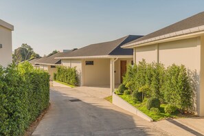 A row of modern single-family homes with a paved driveway and well-maintained landscaping. - Valentine Village (Koh Samui)