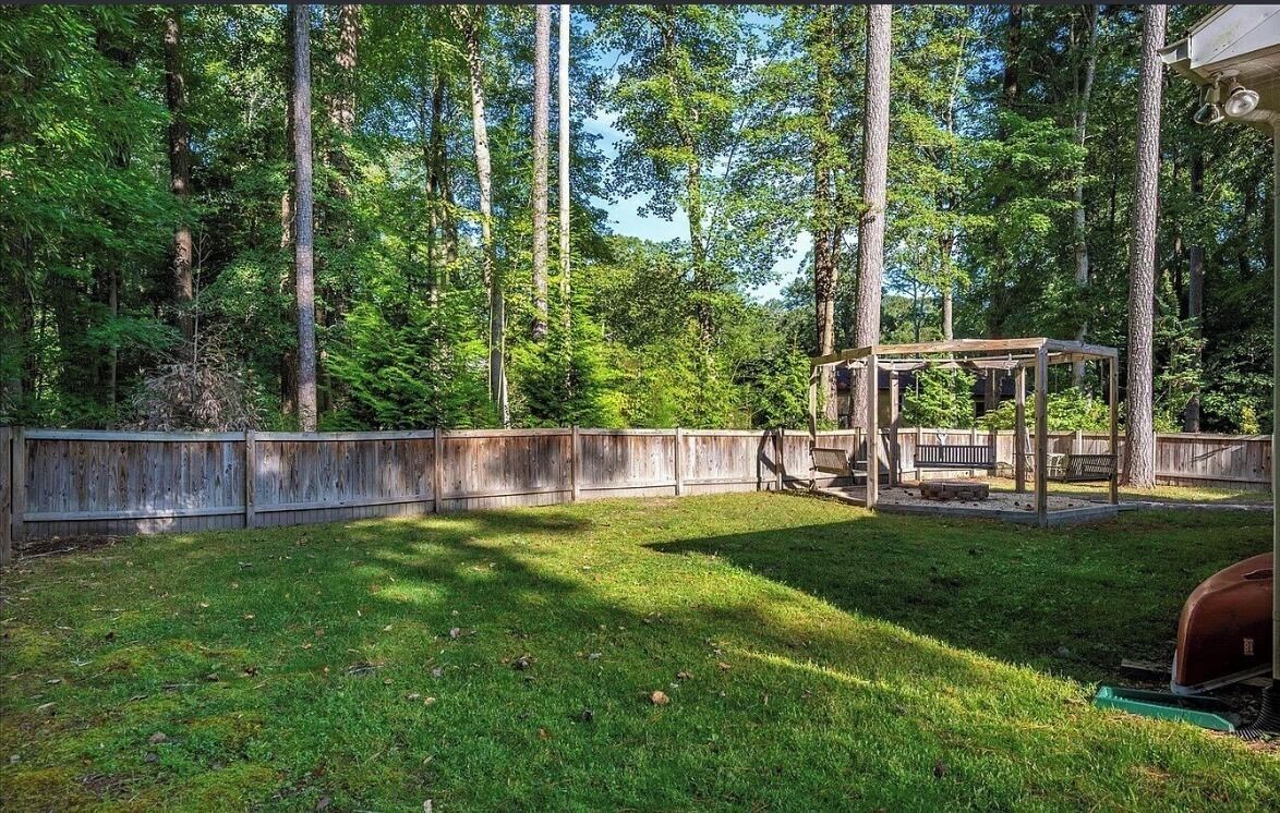 Un jardin avec une terrasse en bois, un kiosque et un barbecue.