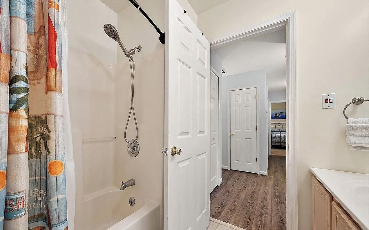 Un baño con ducha, inodoro y lavamanos. Hay una puerta que da a otra habitación.