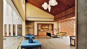 Een ruime lobby met een houten plafond, moderne zithoek en een keuken in de achtergrond.
