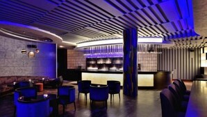 Een moderne bar met een gebogen toonbank, blauwe zitplaatsen en een opvallend plafondontwerp.