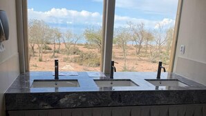 Un baño con dos lavamanos, un perchero y vistas al paisaje desértico.