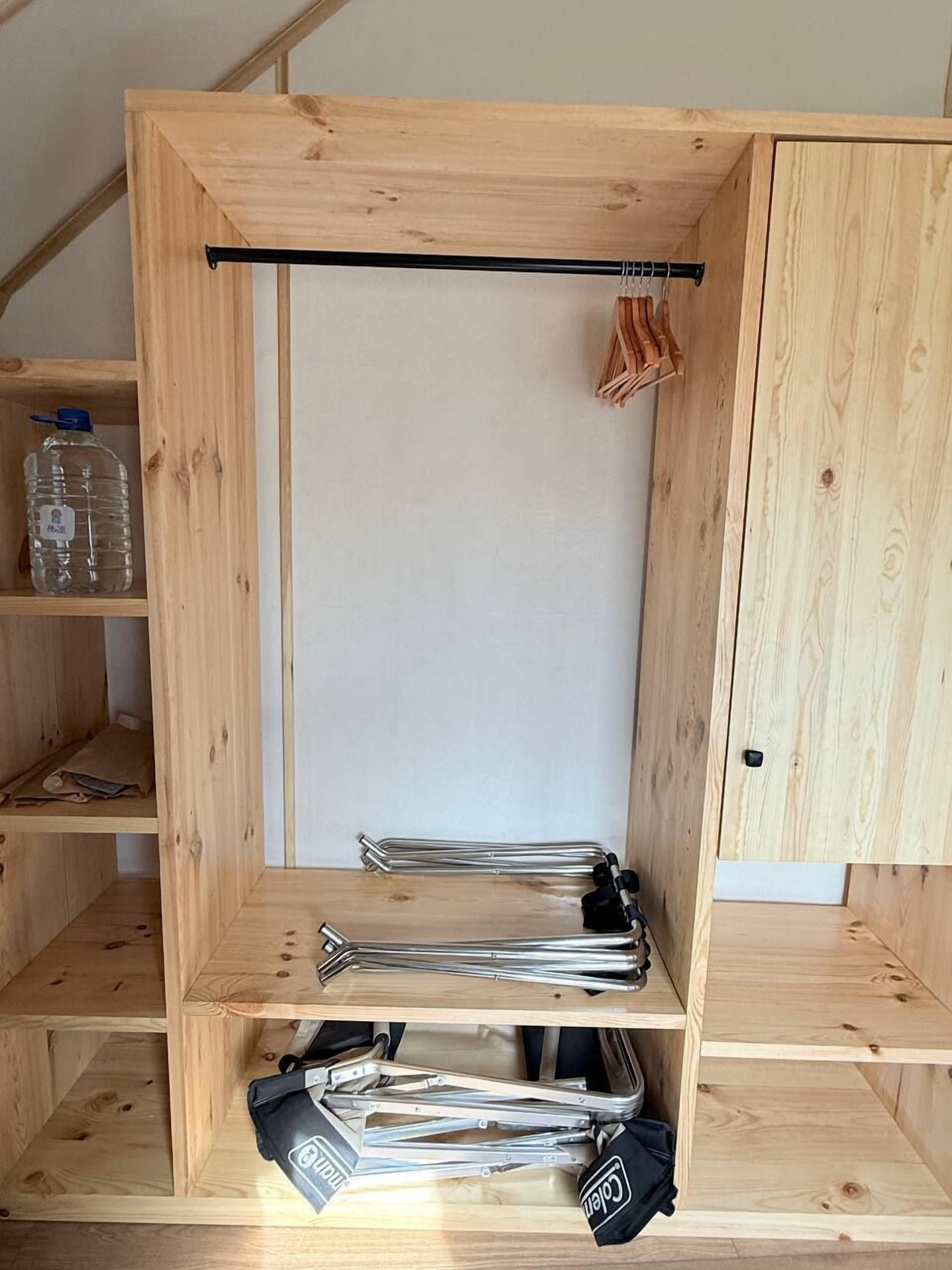 A wooden room with a central whiteboard, shelves with tools, and a water bottle.