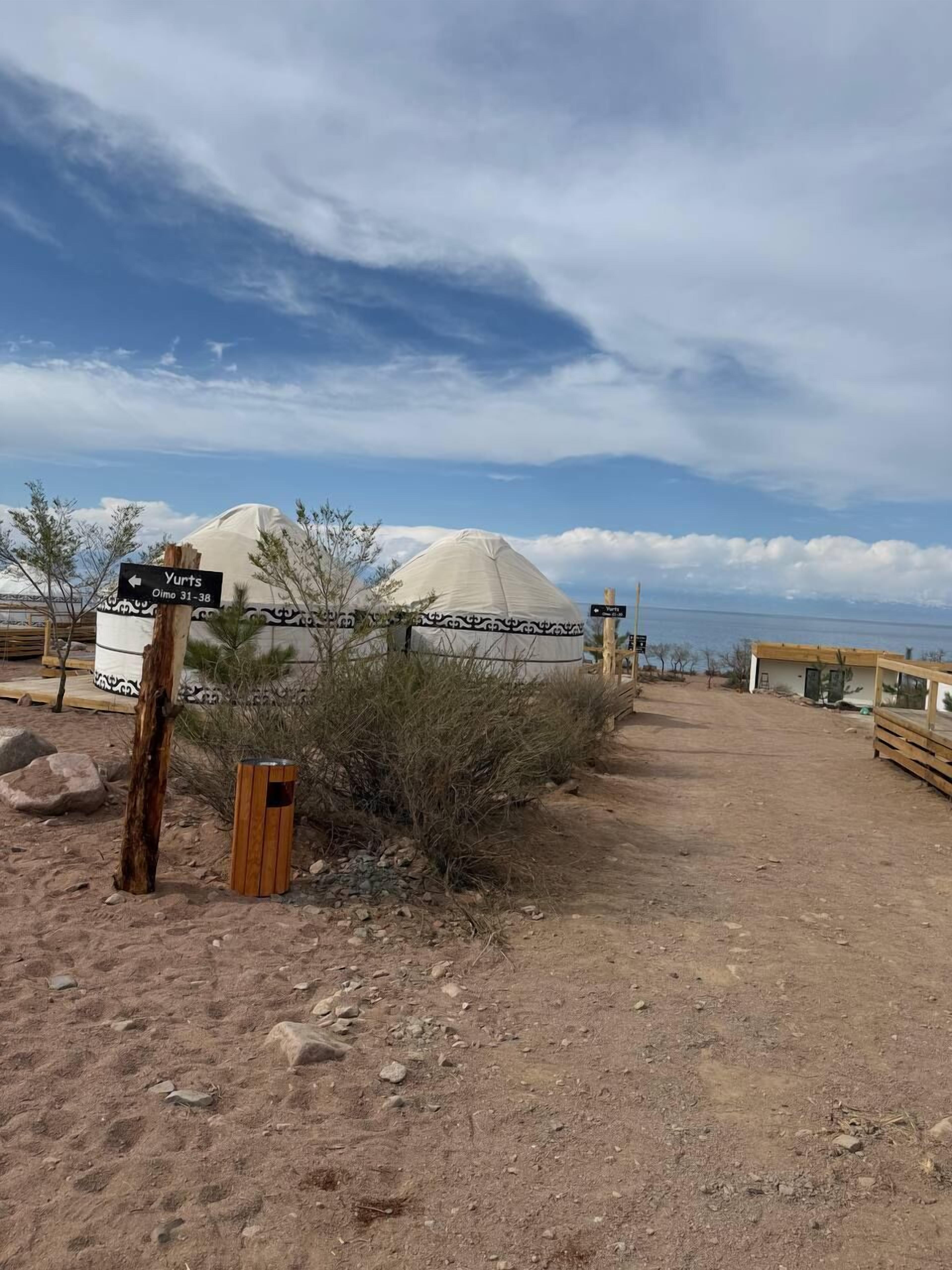 A dirt path leading to a covered structure, a signpost with directions, and a desert landscape.