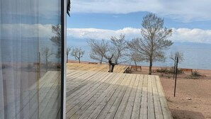 Una terraza de madera que da a una playa con vista despejada al mar y árboles.