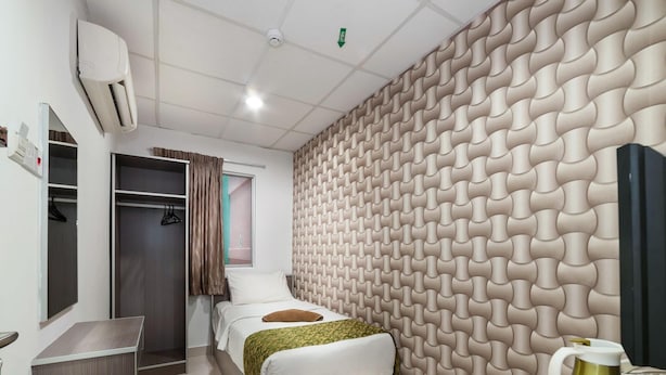 A modern hotel room with a bed, a wardrobe, a vanity with a mirror, and a wall with a textured pattern. - Lacomme Inn (Kuala Lumpur)