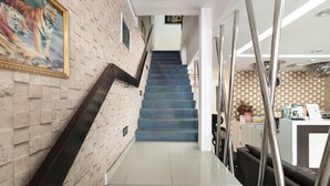 A staircase with a blue carpet leading to a reception area with a counter and chairs. - Lacomme Inn (Kuala Lumpur)
