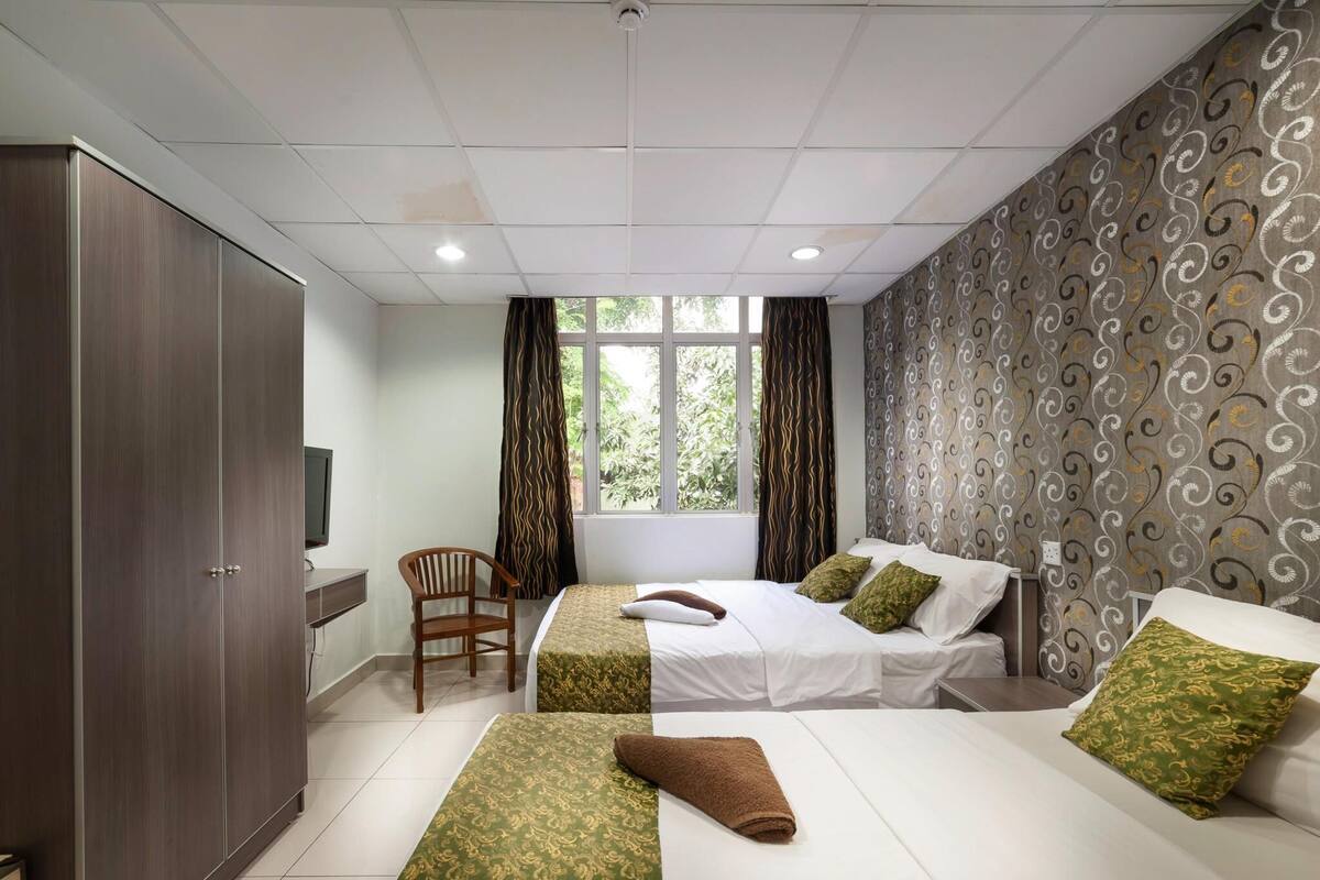 Hotellihuone, jossa on kaksi sänkyä, vaatekaappi, työpöytä ja televisio.