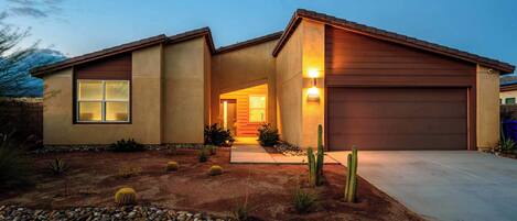 A modern two-story house with a well-maintained front yard featuring cacti and a stone pathway leading to the entrance.