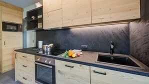Et moderne køkken med træskabe, en sort bordplade og en stålvask.