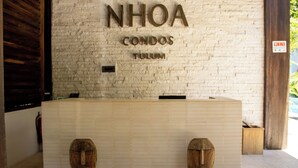 Una reception con un cartello che riporta la scritta 'NHOA CONDOS TULUM'.