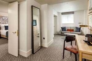 A hotel room with a bed, a desk, a chair, a sofa, and a large mirror. - The Municipal Hotel & Spa Liverpool - MGallery Collection (Liverpool)