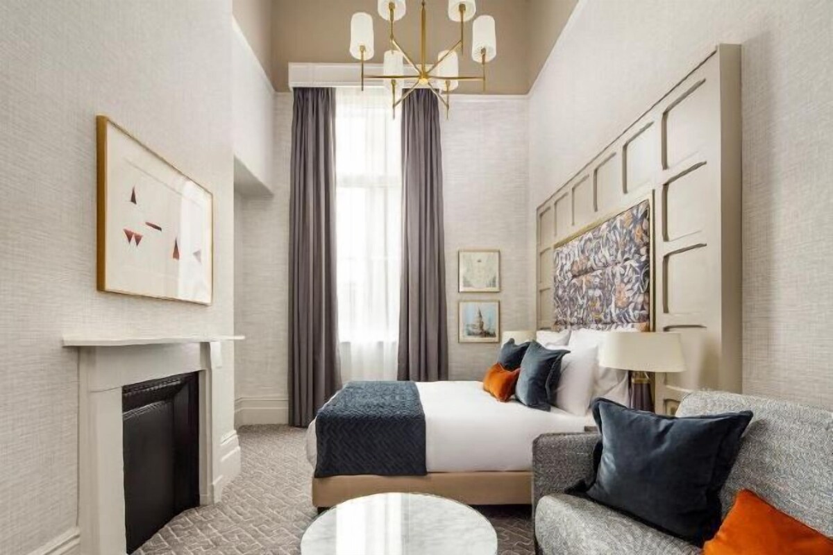 Una camera d'albergo con un letto, un divano, un camino e un lampadario.