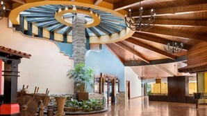 Een ruime lobby met een centraal gelegen trap, een kroonluchter en een modern ontwerp.