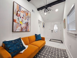 A modern living room with a sofa, a patterned rug, and a large abstract painting on the wall. - Funky Remodeled Otown Bungalow Sleeps 8 (Winter Park)
