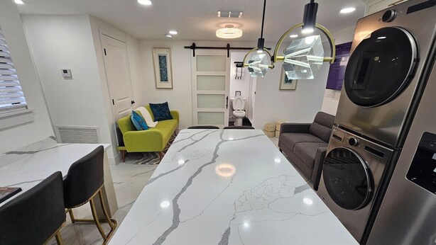 A modern kitchen with a marble countertop, built-in appliances, and a dining area with a green sofa.