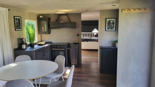 A compact kitchen with a dining area, featuring a round table and chairs, a built-in stove, and a small cabinet.