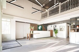A spacious lobby with a reception desk, a staircase, and a view of the sky.