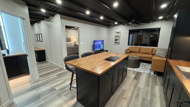 A modern kitchen with a central island, dark cabinetry, and a grey herringbone floor pattern. - Modern Loft w/ Red Rock Views - Downtown St George (St. George)