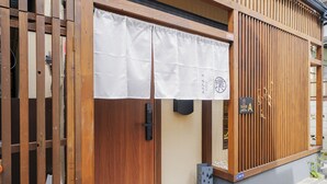 A traditional Japanese building with a wooden door, a white curtain, and a sign with Japanese characters. - Haku Yuukyu-no-Ten Japanese Style Residence/ Rarely available due to Tokyo's cold winters/ Rarely available due to Tokyo's cold winters/ In the heart of Shinjuku/ 4 minute walk from East Shinjuku Station/ Max 7 people/ Newly renovated/ Family friendly (Shinjuku City)