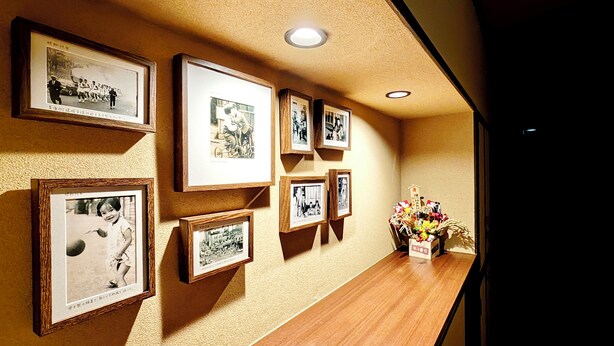 A hallway with framed photographs on the wall and a wooden shelf with a vase of flowers. - Haku Yuukyu-no-Ten Japanese Style Residence/ Rarely available due to Tokyo's cold winters/ Rarely available due to Tokyo's cold winters/ In the heart of Shinjuku/ 4 minute walk from East Shinjuku Station/ Max 7 people/ Newly renovated/ Family friendly (Shinjuku City)