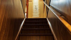 A wooden staircase with a handrail, leading to a door with a paper hanging on it. - Haku Yuukyu-no-Ten Japanese Style Residence/ Rarely available due to Tokyo's cold winters/ Rarely available due to Tokyo's cold winters/ In the heart of Shinjuku/ 4 minute walk from East Shinjuku Station/ Max 7 people/ Newly renovated/ Family friendly (Shinjuku City)