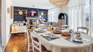 A dining area with a long table set for a meal, surrounded by chairs. - Villa Koraill Glaz by Interhome (Plouescat)