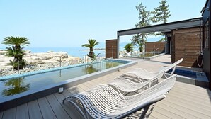 A modern outdoor pool area with a lounge chair, wooden deck, and a view of the sea. - SIOKUMIHAMA  Sea  Side  Villa  HAMATSUZURI (Miyazu)